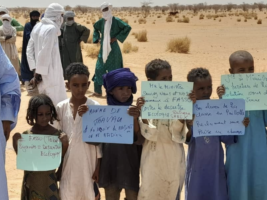 Children in the Ahaggar Desert (Algeria) hold handwritten signs in French