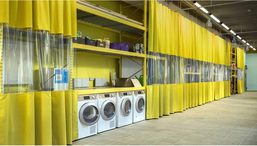 The image shows an industrial setting, likely a workshop or warehouse, where flexible PVC curtains are used to create partitioned areas.