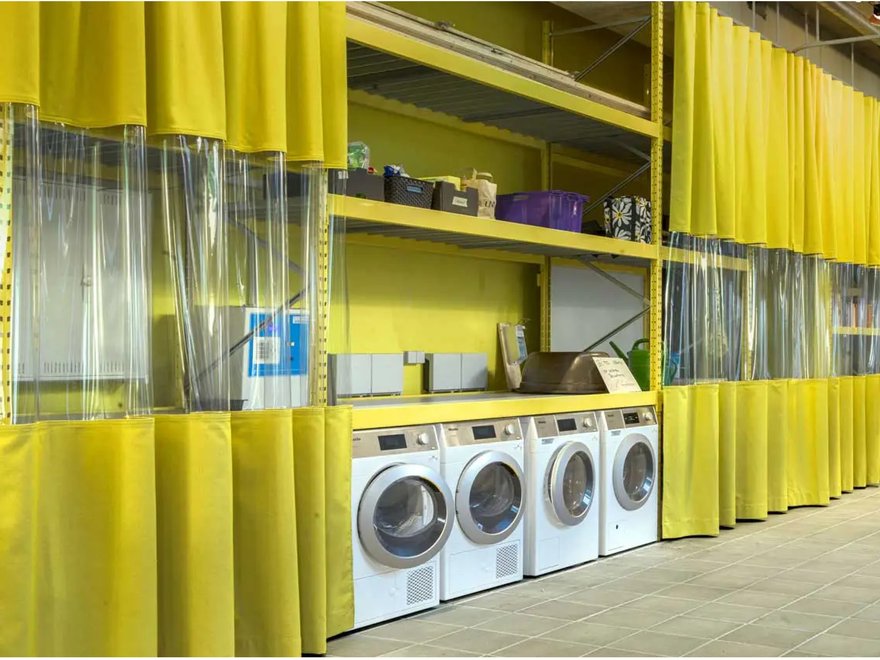 The image shows an industrial setting, likely a workshop or warehouse, where flexible PVC curtains are used to create partitioned areas.