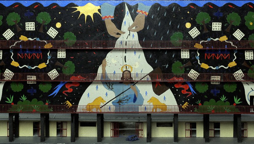 A colorful, multi-layered mural depicting a stylized figure with hands reaching upwards, possibly representing creation or guidance, against a dark, starry background with trees, patterns, and abstract shapes.
