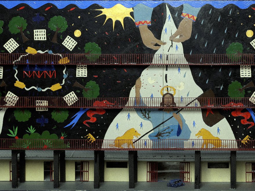 A colorful, multi-layered mural depicting a stylized figure with hands reaching upwards, possibly representing creation or guidance, against a dark, starry background with trees, patterns, and abstract shapes.