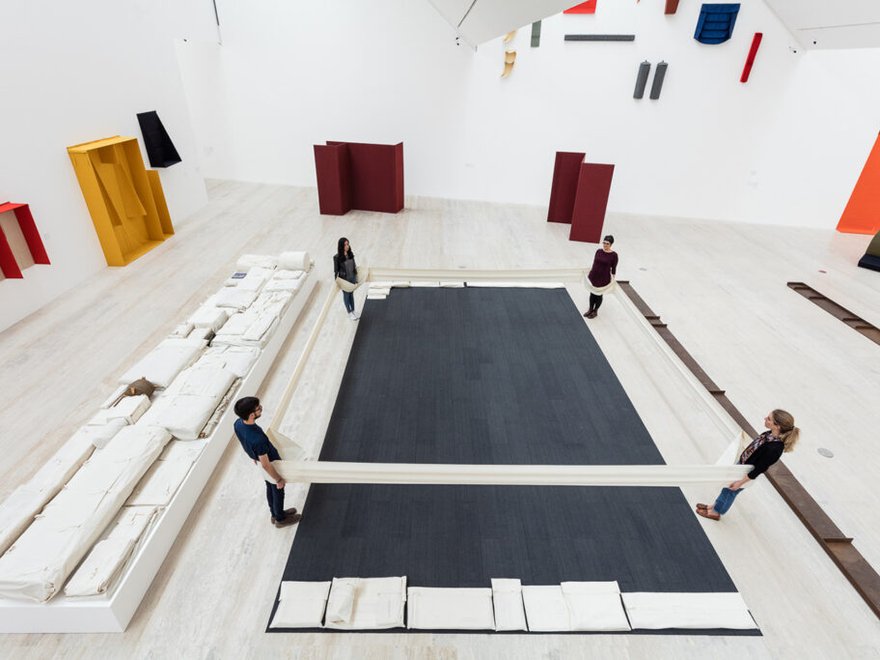 Ariel view of a gallery space with large colourful structures and rows of folded fabric