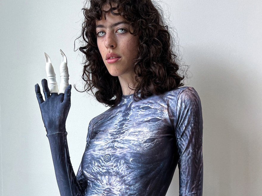 A young woman wears a futuristic top that looks like shiny alien skin