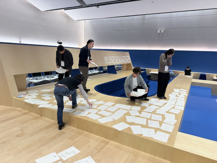 Workshop in a custom course in Gunma, Japan. Participants are laying out worksheets on the ground in a setting that looks like a conversation pit.