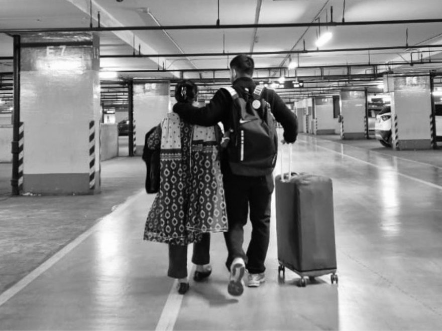 A black and white image of a man and a woman walking with a suitcase