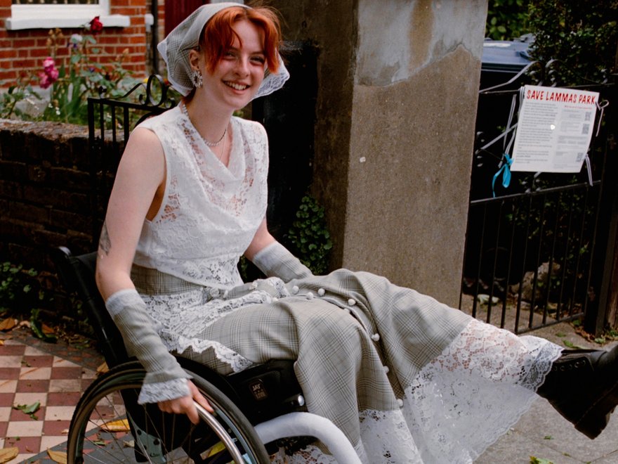 A female wheelchair user models a stylish outfit on an urban street