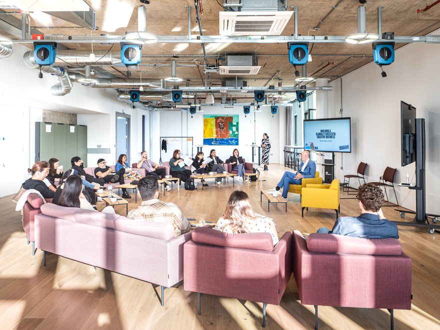 A session at masterclass: participants sit on sofas in a semicircle, listening to the presenter.