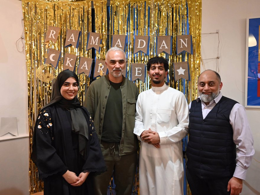 A group of people stand smiling in front of a banner