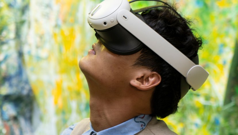 A person in a VR headset looks up against a brightly coloured abstract background