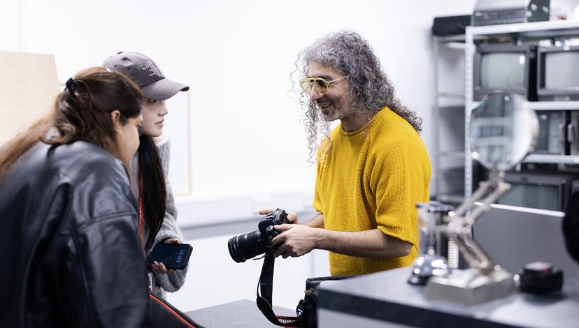 a brightly dressed technician helps students with camera hire
