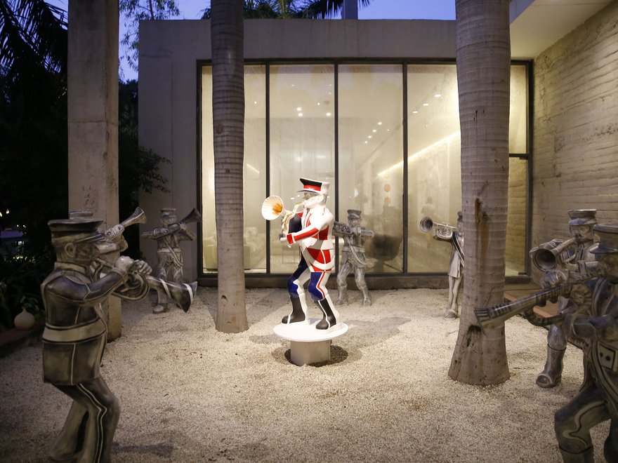 Bronze sculptures of musicians in a courtyard, with one central figure painted in a colourful uniform playing a trumpet.