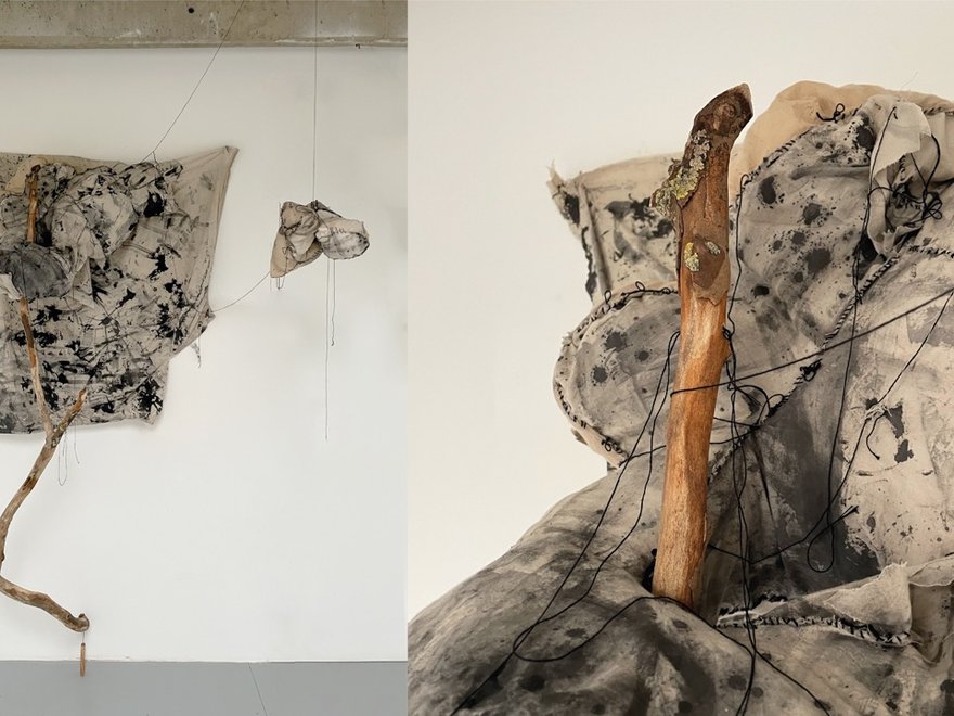 Ccontemporary art work consisting of hanging pieces of fabric and branches