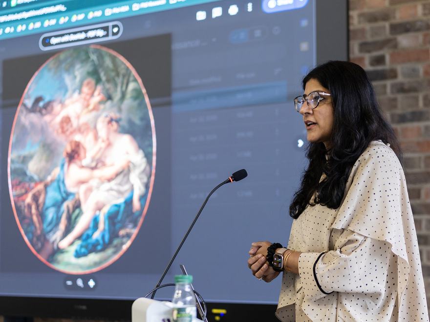 a person stands at a podium delivering a talk in front of a screen