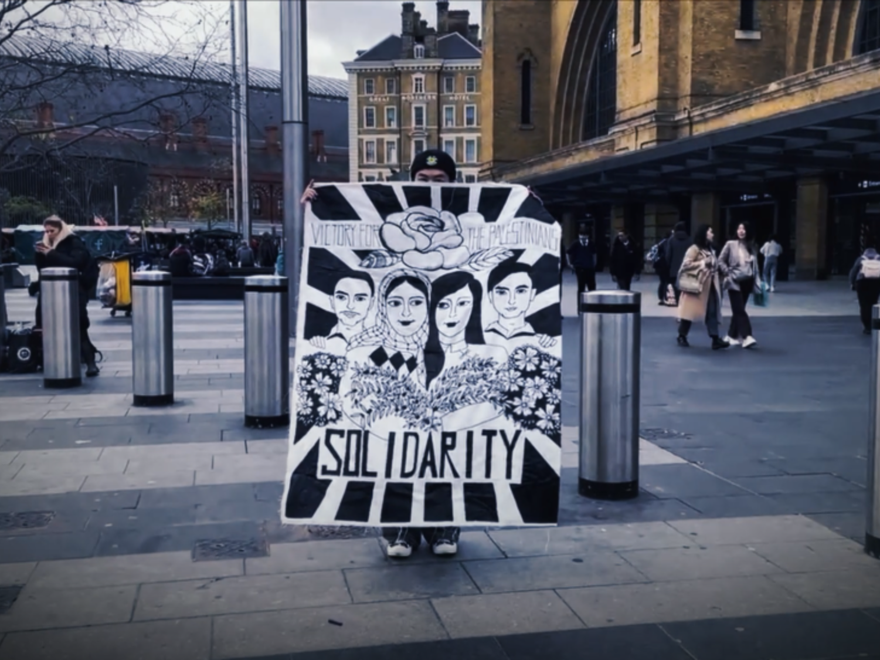 A man holds a banner in support of Palestine in a public street