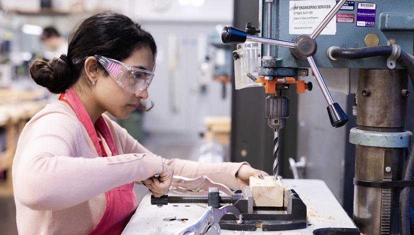 a female student using a drill press