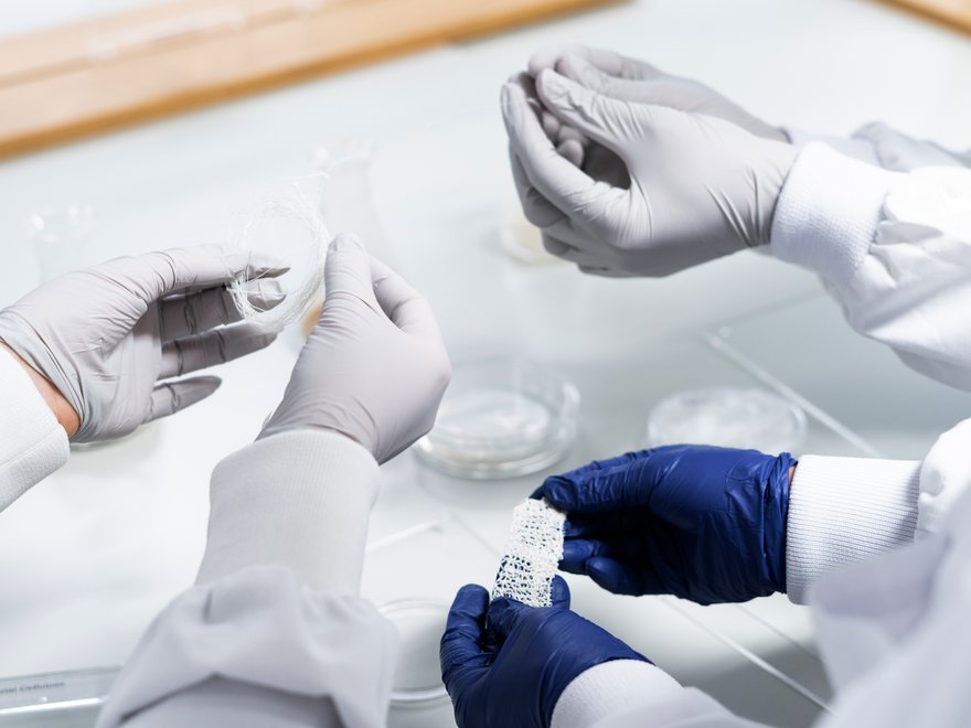 A close-up of three people wearing surgical gloves examining samples