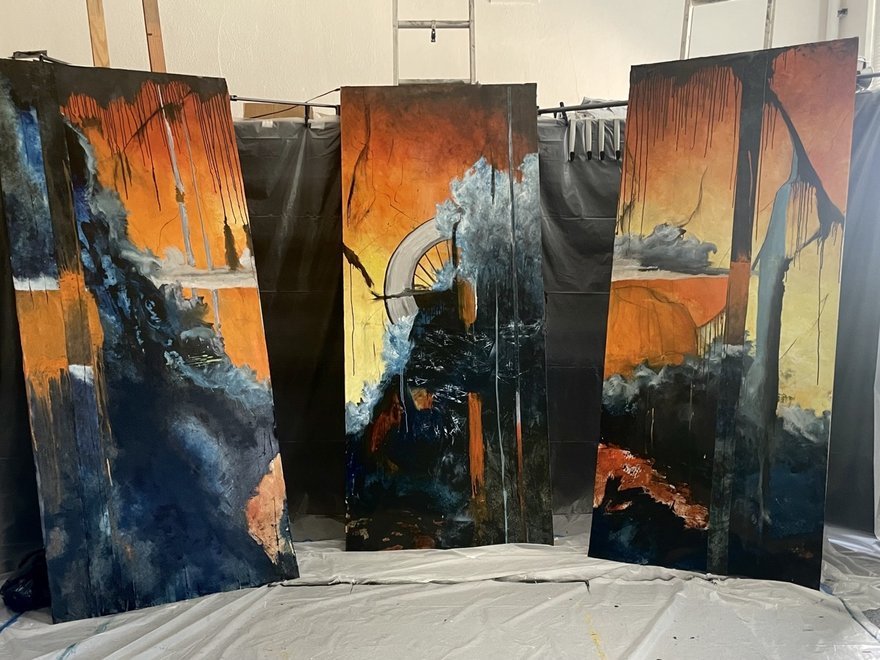 Three painted canvases in a gallery space, featuring abstract orange and black artwork.