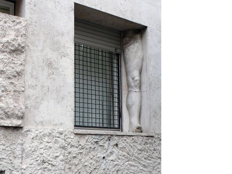 A close-up of a window on a textured, light-colored building facade.