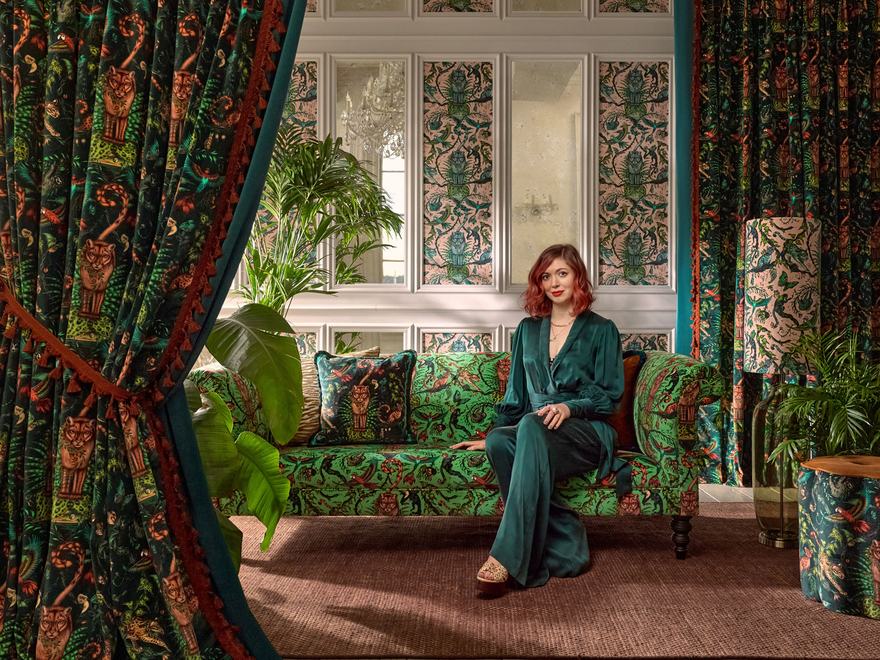 Designer Emma Shipley sitting surrounded by maximalist fabrics and furniture