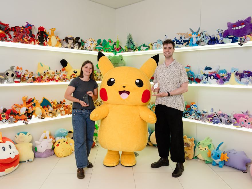 Emily Millward and Joey More pose with Pikachu at The Pokémon Company International offices
