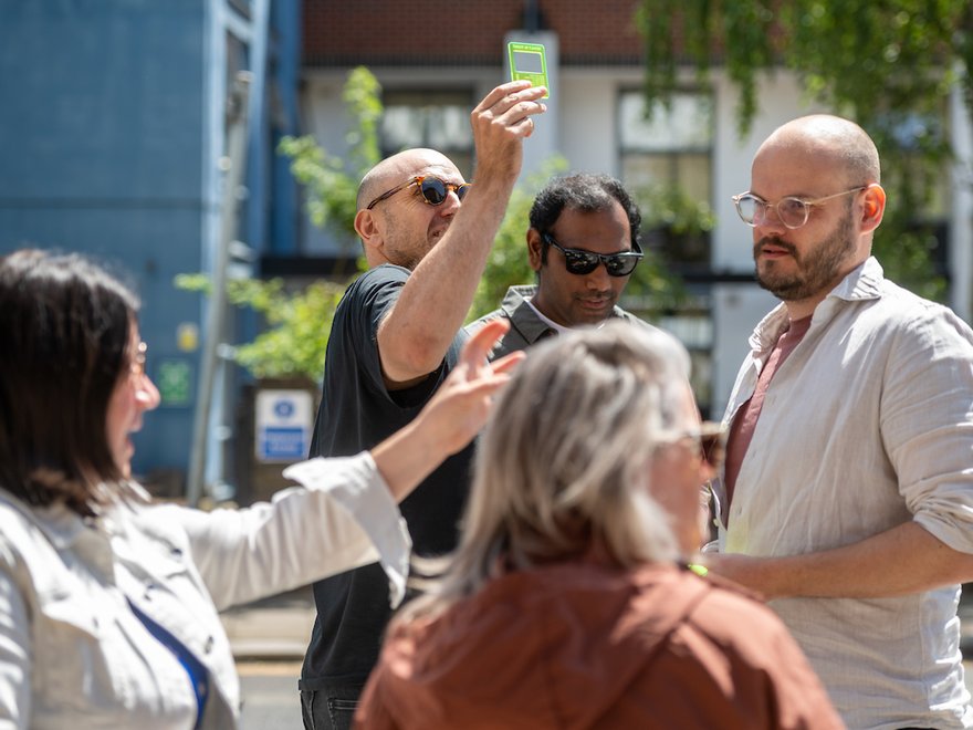 The cohort of 2025 Futures Through Design are outside, working on one of their projects, holding a screenfinder up against the landscapes.