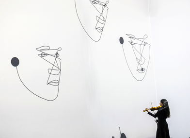 Sue-In Kang performing violin within a responsive visual environment, where projected faces emerge and change in response to the live performance. Photo: Vivaan Thongram