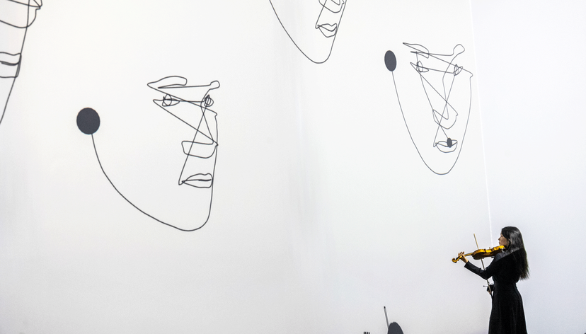 Sue-In Kang performing violin within a responsive visual environment, where projected faces emerge and change in response to the live performance. Photo: Vivaan Thongram