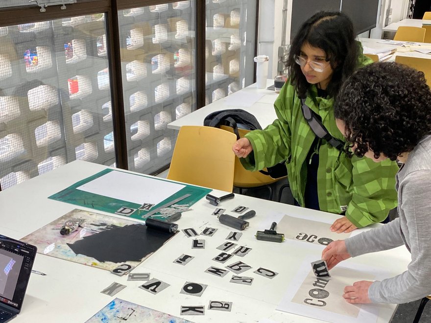 Two women look over a desk with typography cut outs