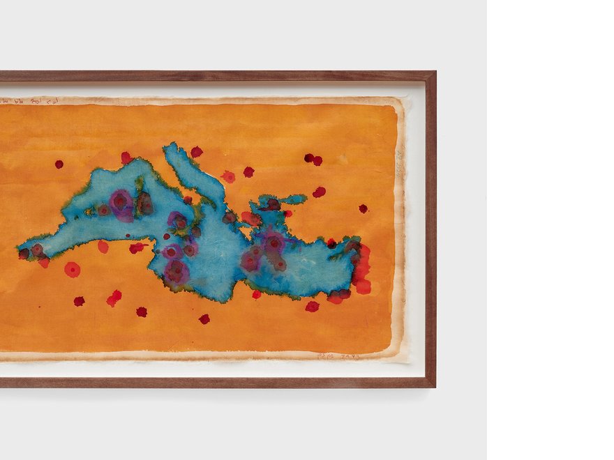 Framed painting of a blue form in the shape of the Mediterranean sea on a yellow background, splattered with red dots.