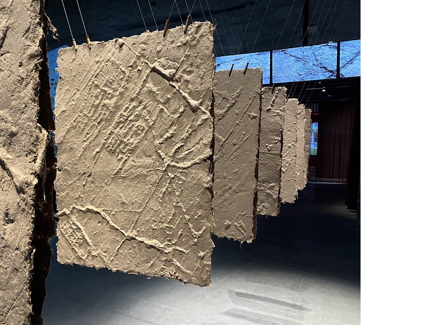 Large panels covered in a thick textured clay suspended from the ceiling