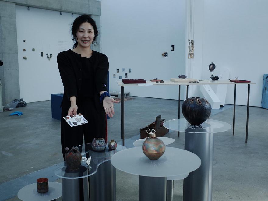 a person stands proudly beside the work they are exhibiting