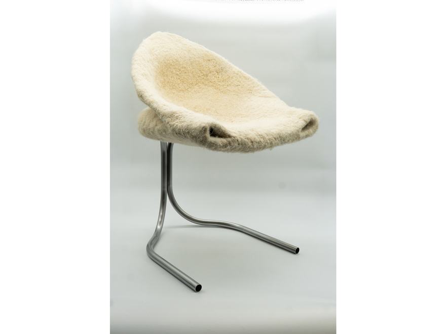A sculptural chair featuring a thick, off-white felted wool seat supported by a minimalist, tubular metallic frame.