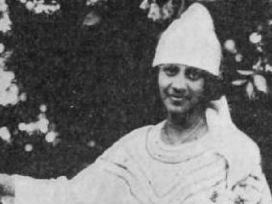 A black and white image of a smiling woman with a hat on