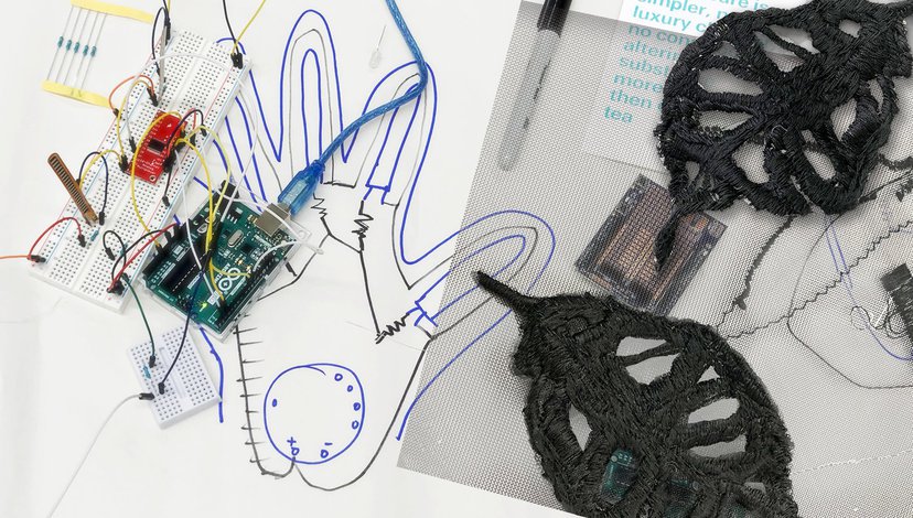 Close up detail of a motherboard and wires against sketches for a robotic hand.