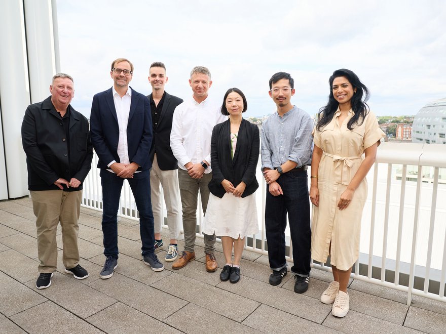 A group of sevent individuals standing together on a balcony at RCA Battersea campus.