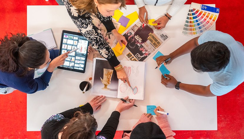 A group of RCA students collaborate on a creative project with pens and post it notes around a table