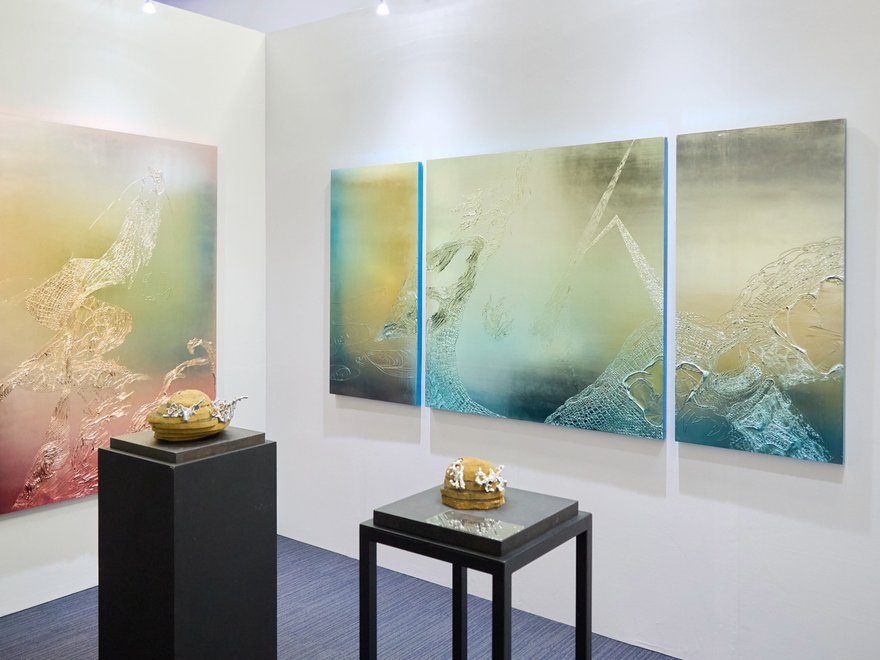 An exhibition of silvery colourful canvases with two sculptures on plinthes