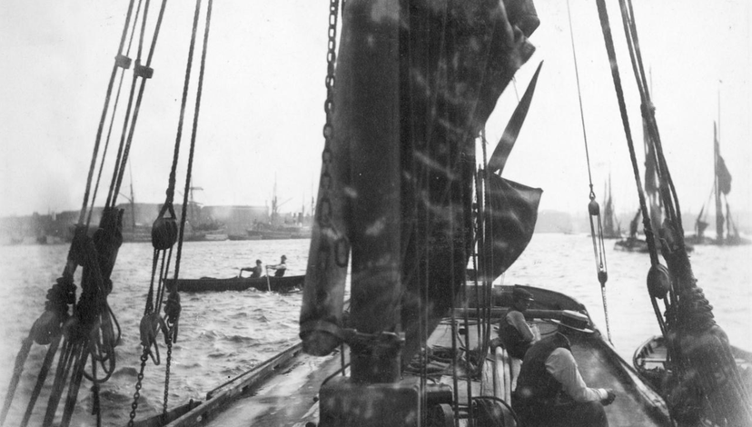 A black and white historical photo of a boat on a river