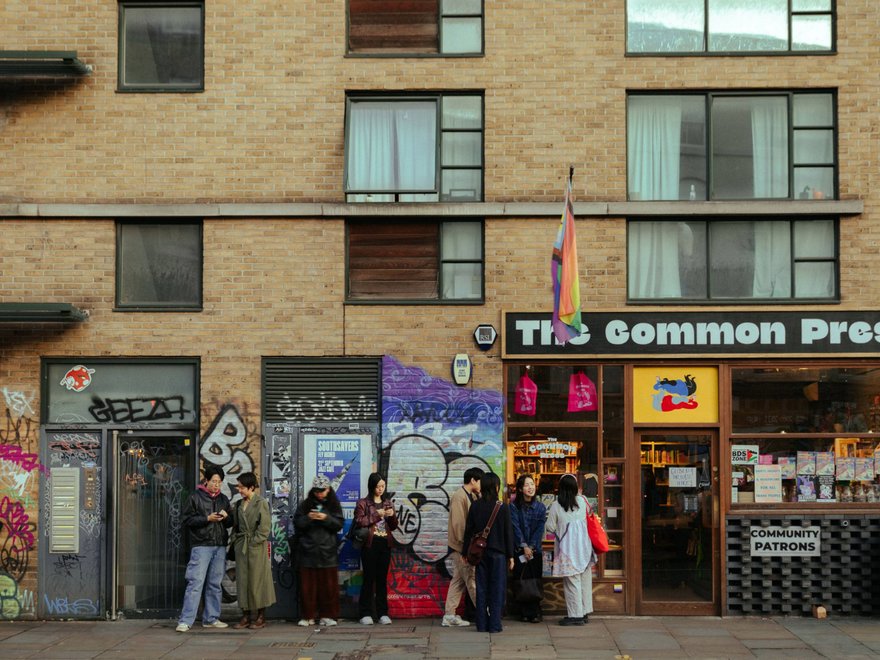 a group of people stand outside a shop that says common press