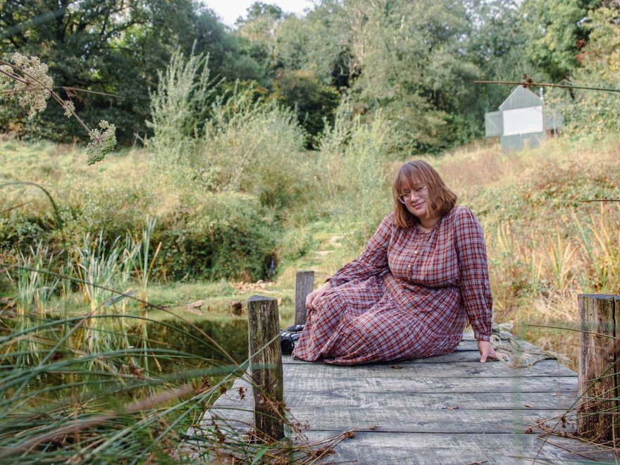 A young woman lies on a diving board plank into a lake