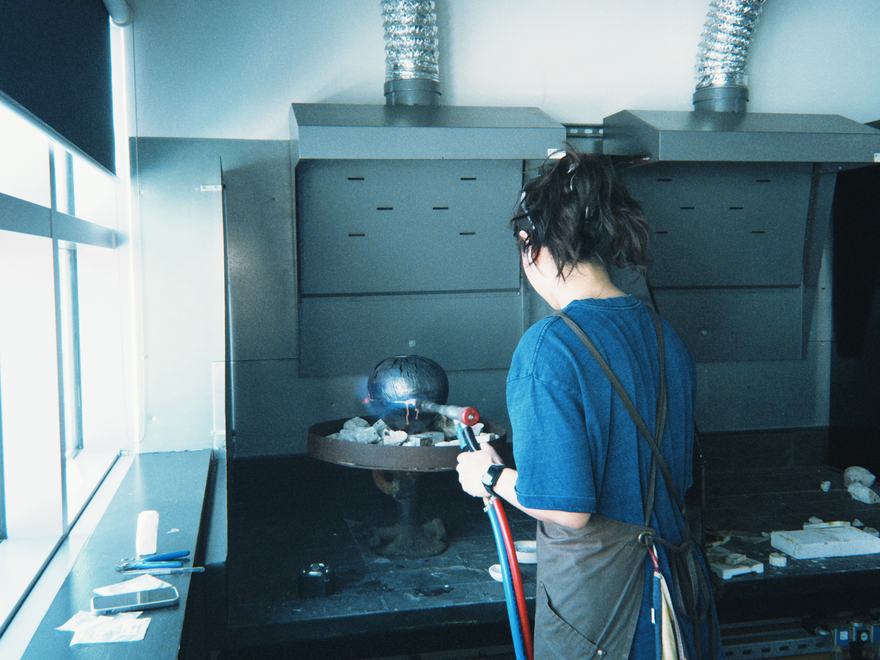 person seen from behind working in the metal work forge