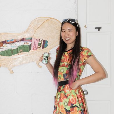 YiMiaoShih in a bright fruit patterned dress in front of an illustration