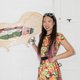 YiMiaoShih in a bright fruit patterned dress in front of an illustration