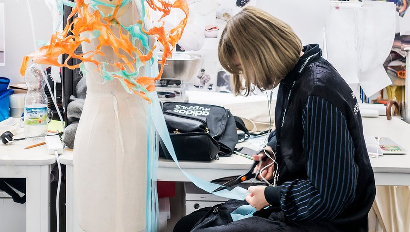 A person cutting light blue fabric in a design studio.