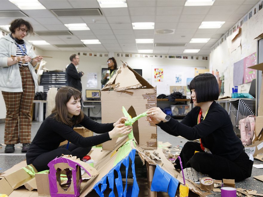 Students collaborating on a creative project using cardboard and colorful materials in an art classroom,